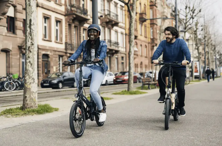 dos personas montando bicicletas eléctricas plegables en una ciudad